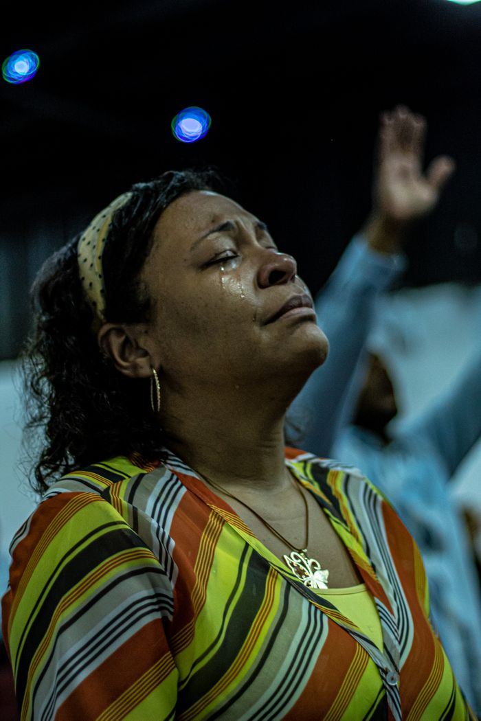 Services Woman shedding tears during a heartfelt moment of prayer indoors, in a spiritual setting.