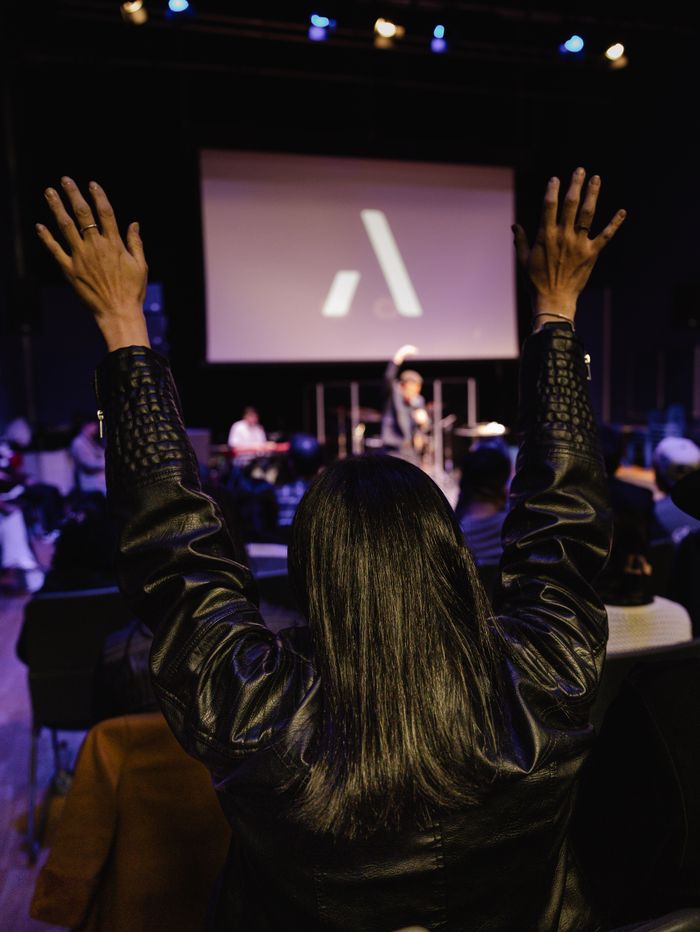 About An enthusiastic worship gathering with people raising hands during a church service